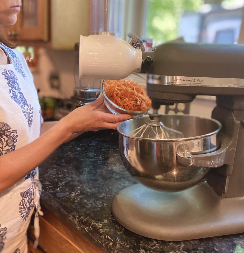 woman mixing carrots in a mixer to carrot cake
