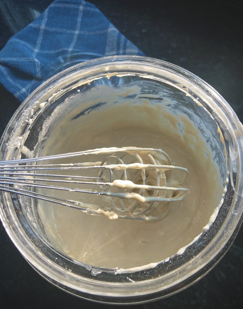 sourdough starter with a whisk inside a glass container