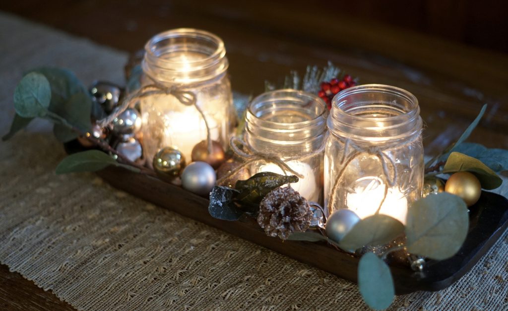 candle centerpiece in mason jars surrounded with eucalyptus