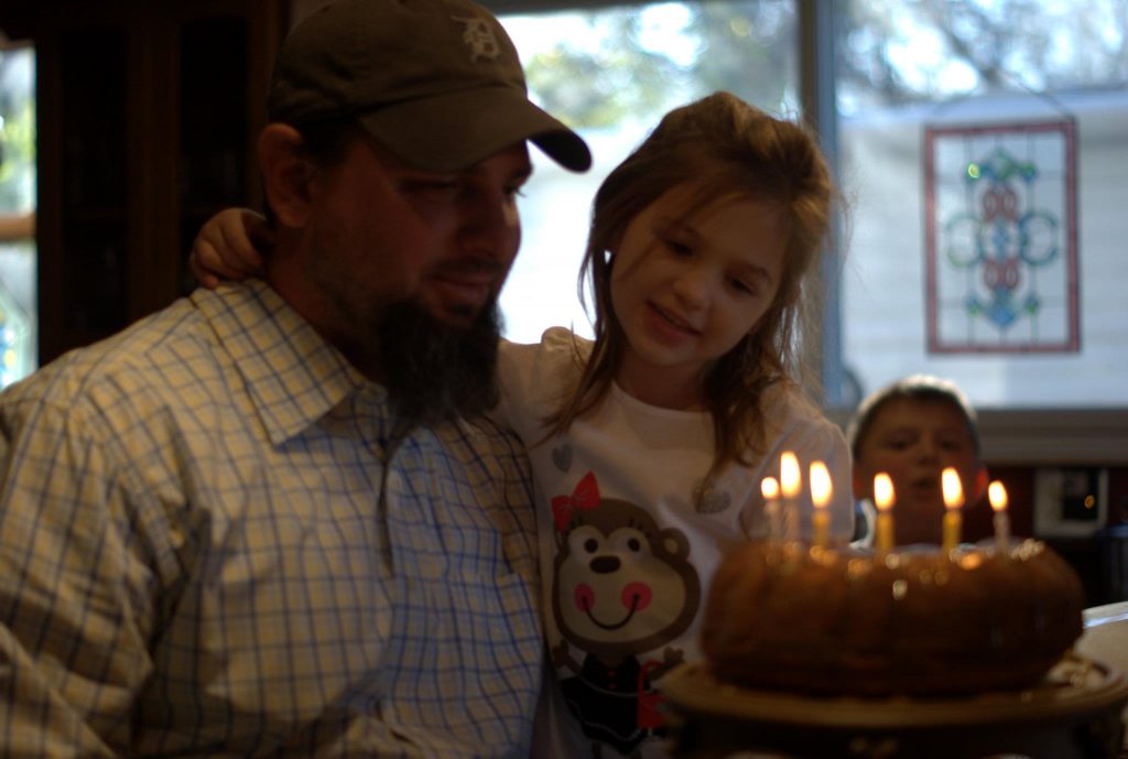 little girl, little boy and father celebrating a birthday with a homemade cake