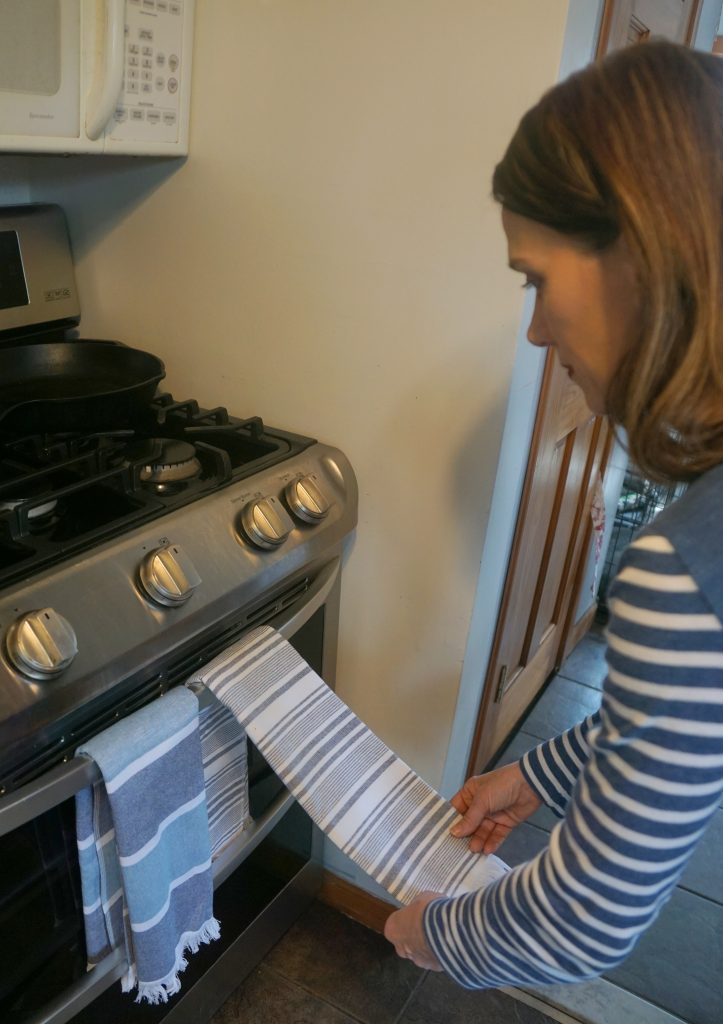 woman placing a blue and white towel on a stove handle
