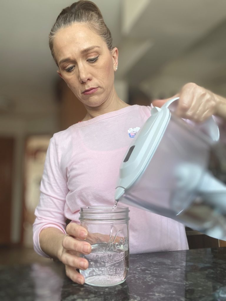woman pouring water into a mason jar