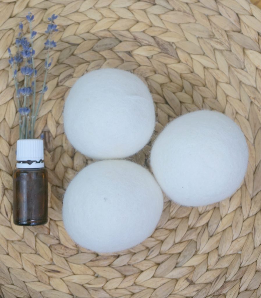 dryer balls on a woven mat with lavender sprigs and essential oil bottle