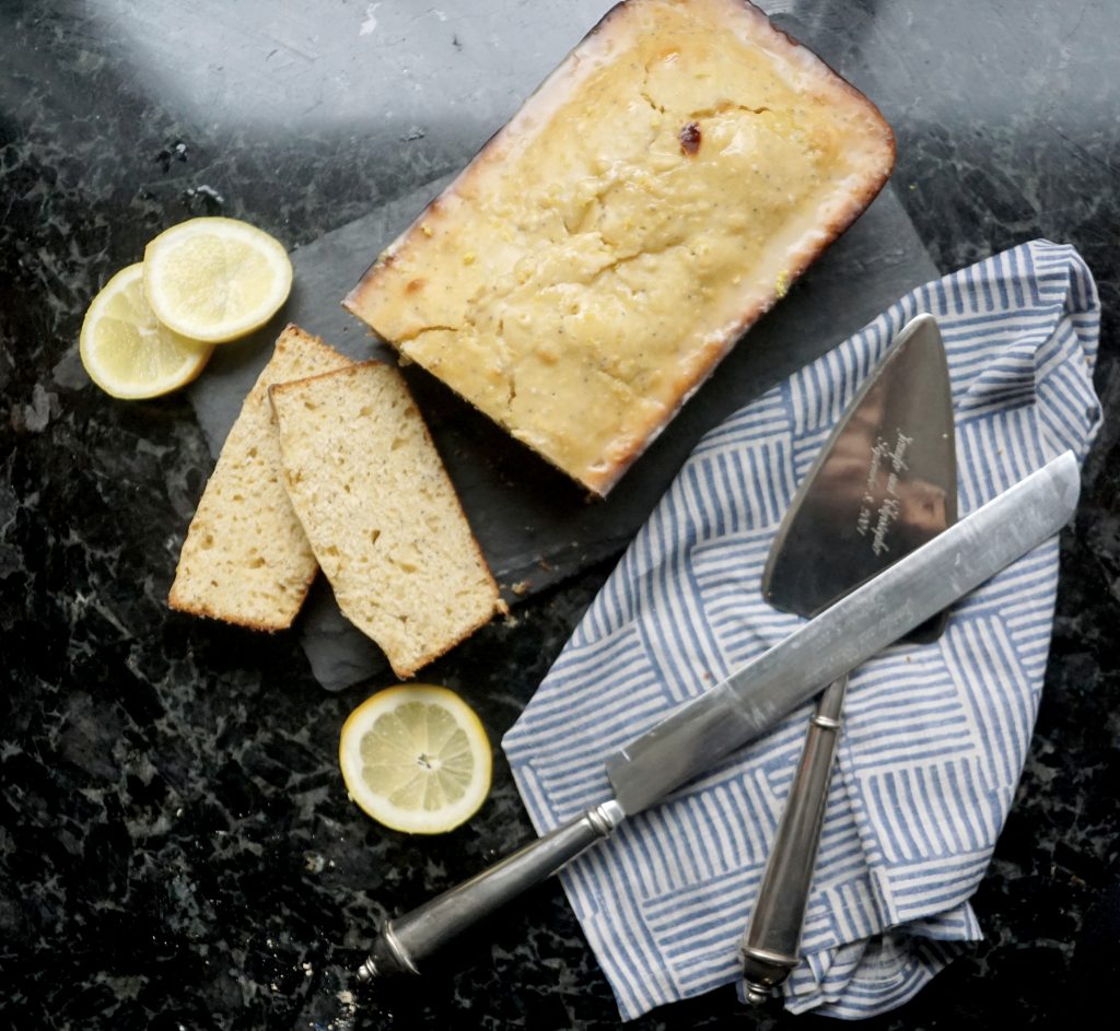 from scratch lemon loaf displayed with lemons and a cake cutter