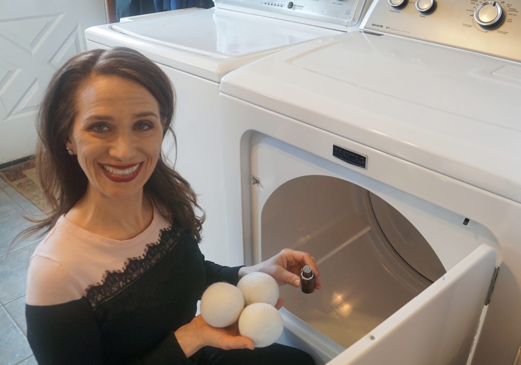 woman placing essential oils and dry ball in dryer