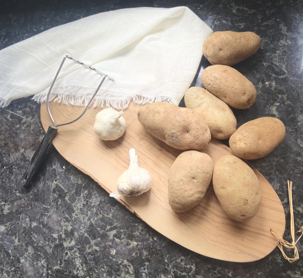 display of russet potatoes, garlic on a wooden tray