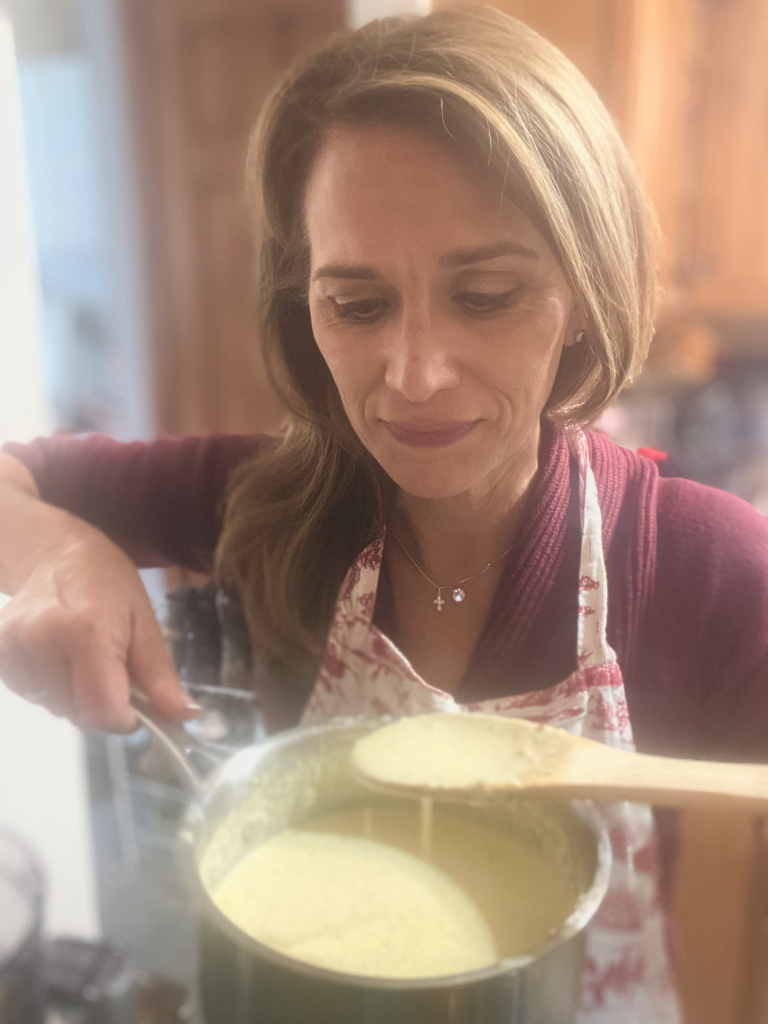 woman tasting Alfredo Sauce with a wooden spoon