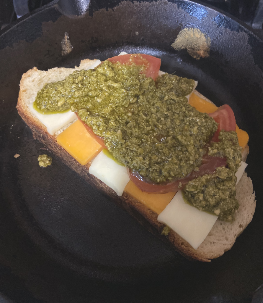 a grill cheese layered with cheese, tomato and pesto