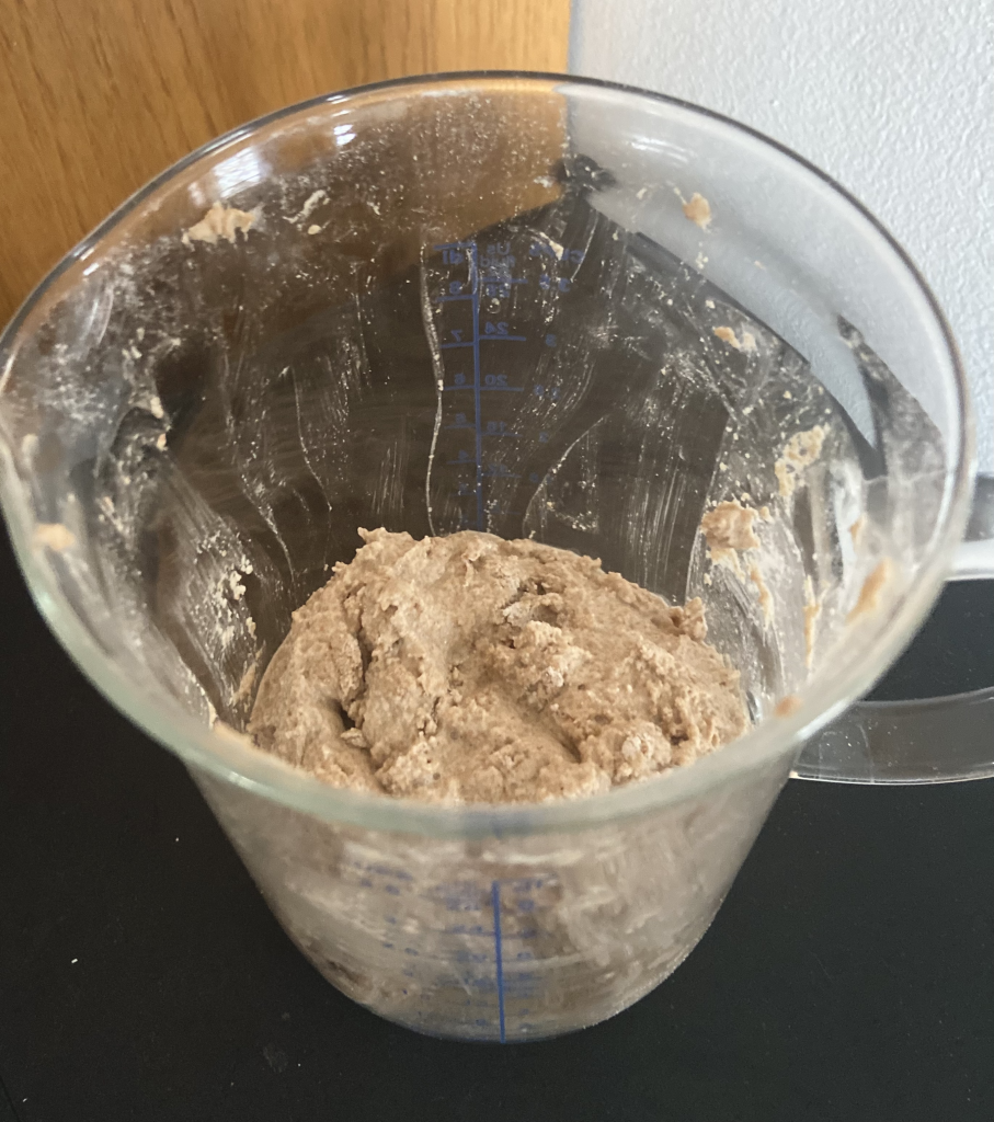 whole wheat flour soaking in a glass measuring glass cup