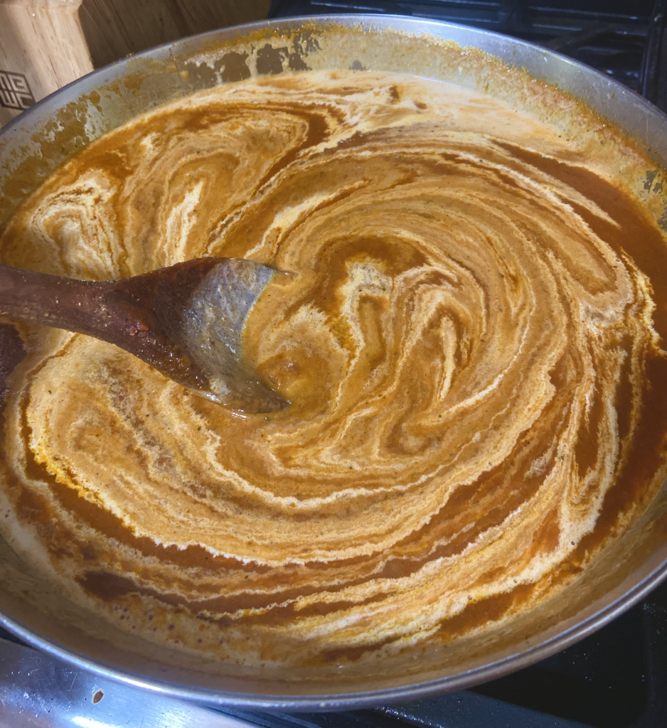 Creamy Vodka Pasta sauce being stirred with a wooden spoon.