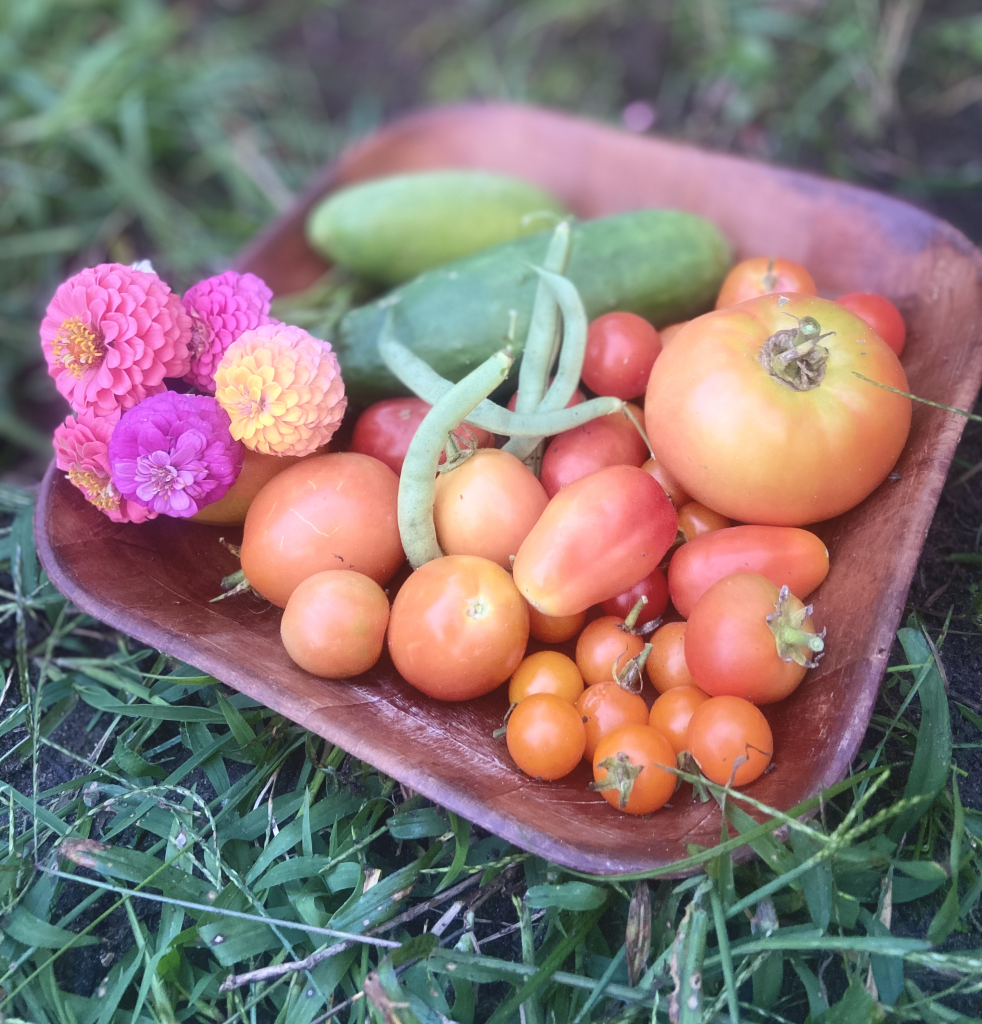 a wood bowl full of produce from a summer harvest