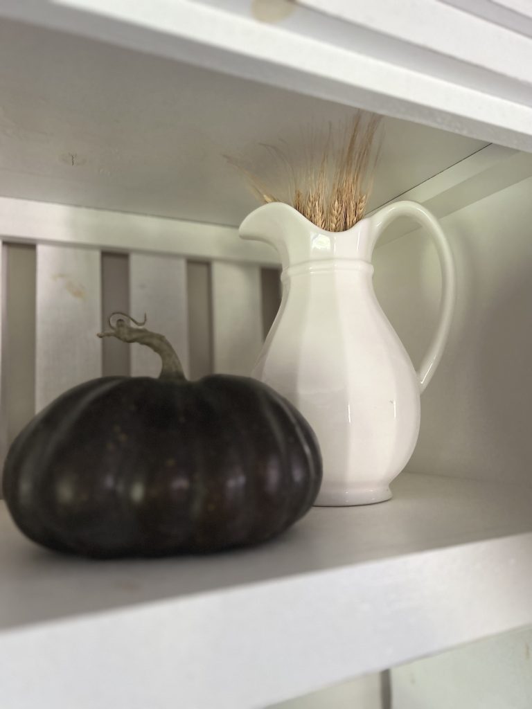 white pitcher next to a moody dark pumpkin