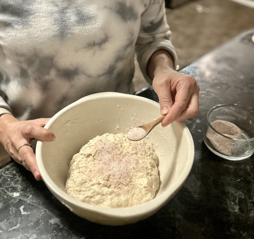 woman adding salt to sourdough French bread