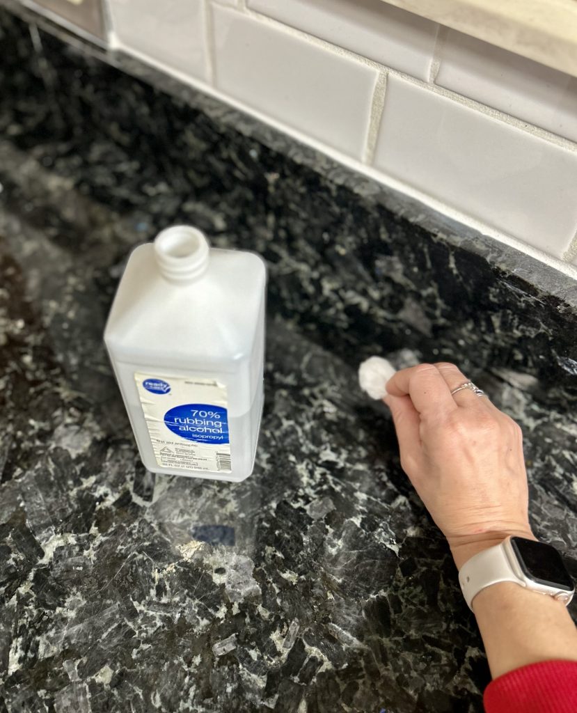 woman using rubbing alcohol to clean granite counters